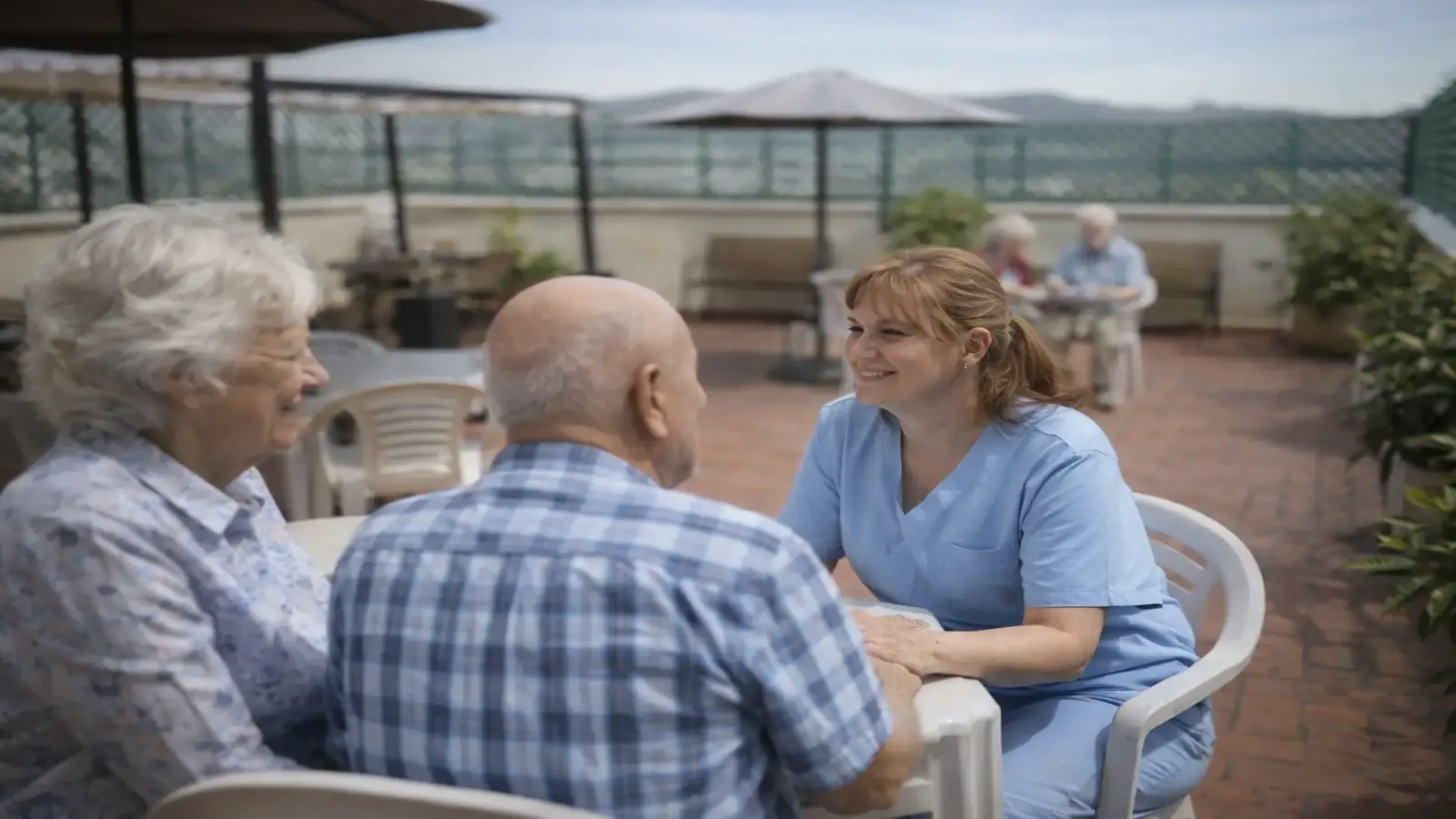 Cuidadora acompañando a pareja mayor en terraza de residencia especializada en Alzheimer en Barcelona